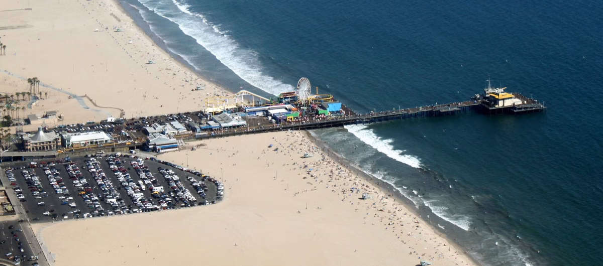 Aerial view of the Santa Monica Pier with the beach and parking lots beside it