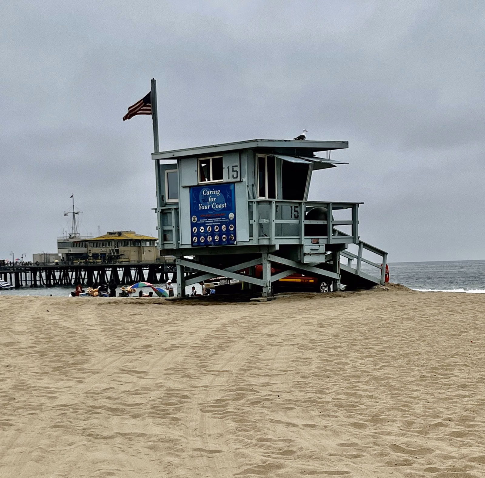 A lifeguard tower on the sand with the Santa Monica Pier behind it