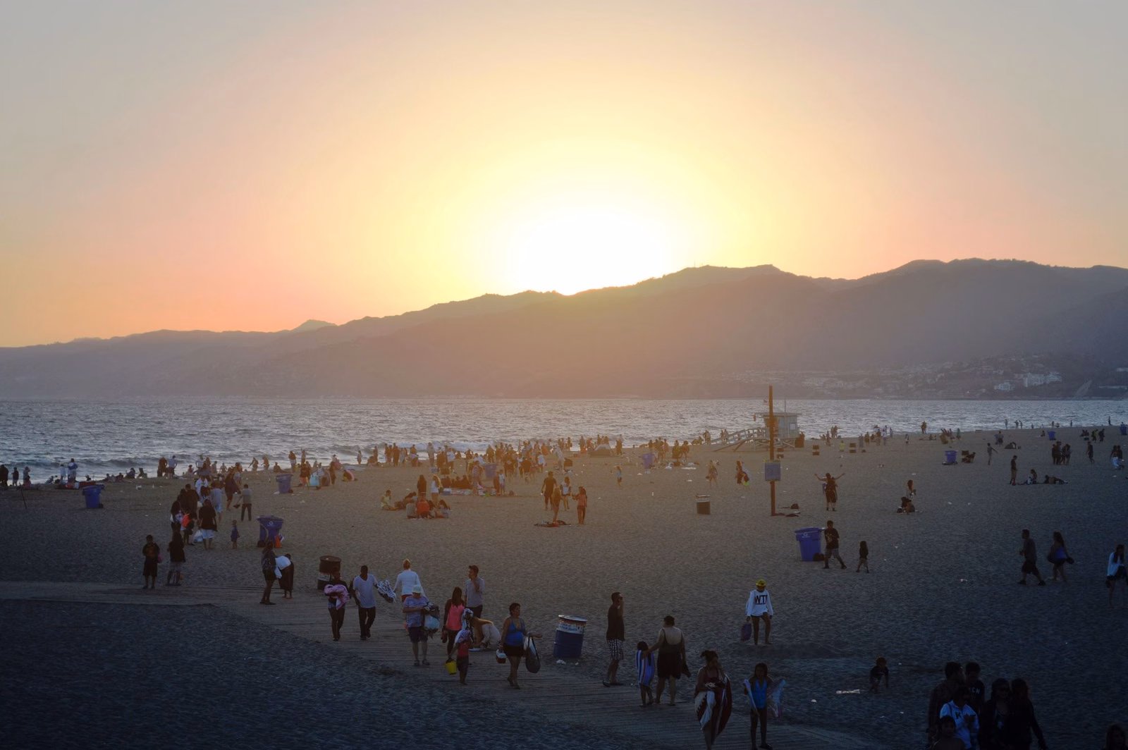 Sunset over Santa Monica Bay and the mountains, with people on the beach