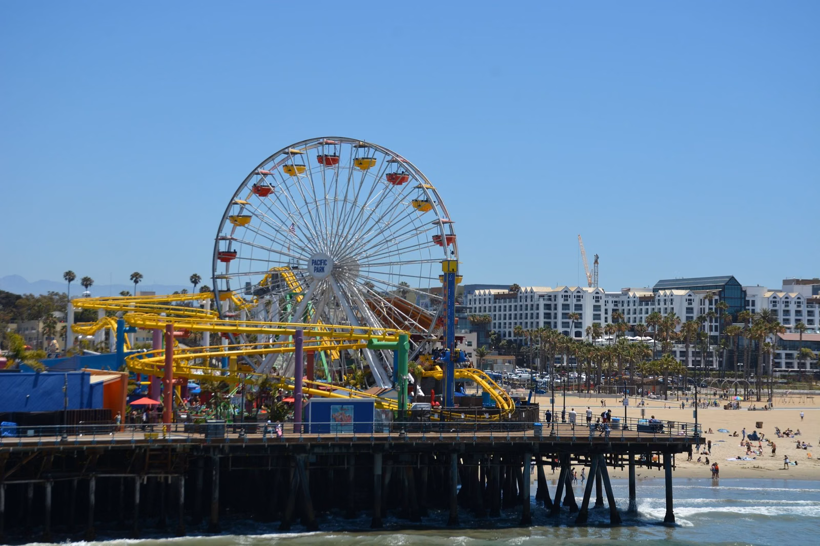 The Santa Monica Pier with Pacific Park's Ferris wheel and roller coaster over the beach