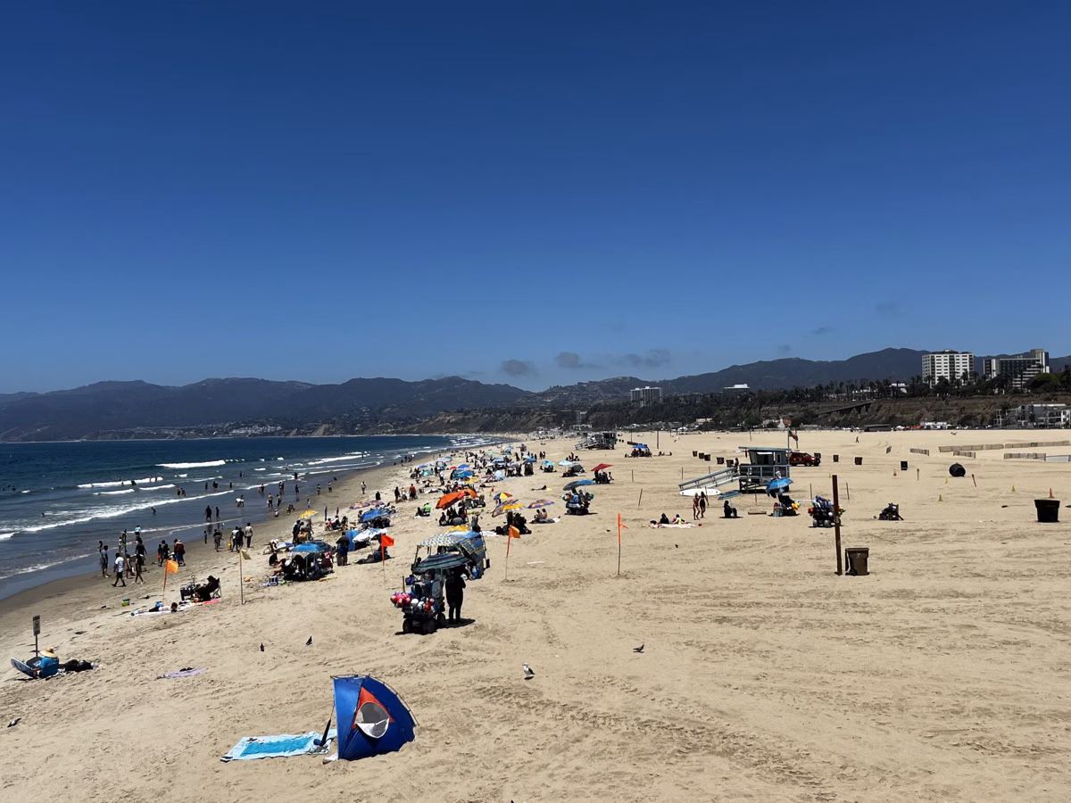 A busy summer day on Santa Monica State Beach with the mountains in the distance